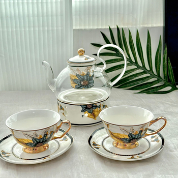Set din ceramică franceză pentru ceai de după-amiază, cu ceainic, căni și farfurioare de cafea cu detalii aurii, căni pentru ceai cu flori și ceai negru, sigla cafenelei