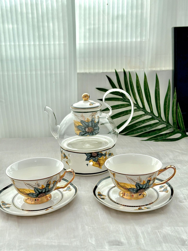 Set din ceramică franceză pentru ceai de după-amiază, cu ceainic, căni și farfurioare de cafea cu detalii aurii, căni pentru ceai cu flori și ceai negru, sigla cafenelei
