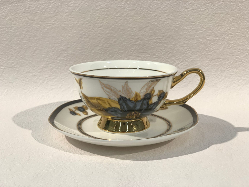 Set din ceramică franceză pentru ceai de după-amiază, cu ceainic, căni și farfurioare de cafea cu detalii aurii, căni pentru ceai cu flori și ceai negru, sigla cafenelei