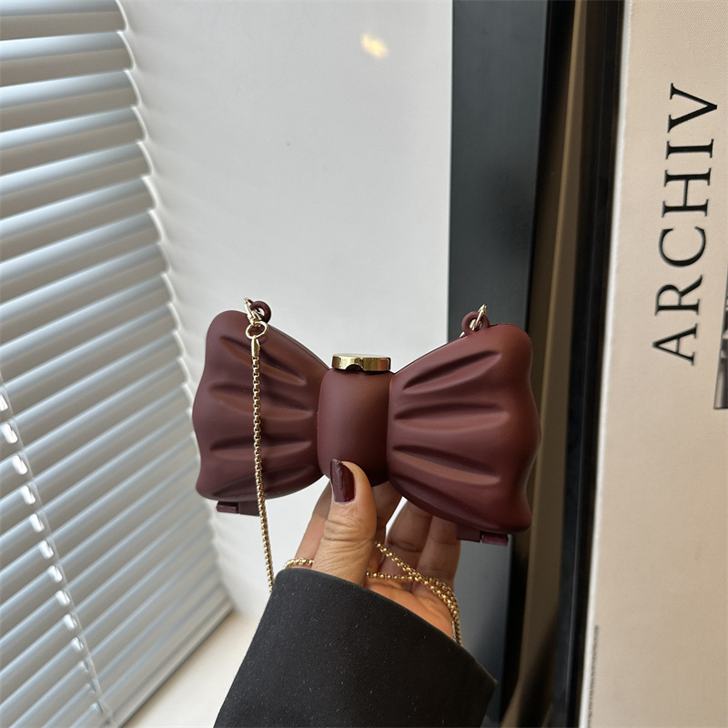 Mini crossbody torbica s metalnom mašnom i bisernom lancem – ženska mini torbica za ruž, proljeće 2025