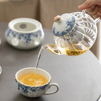 Set ceai în stil englezesc cu căni ceramice încălzite și farfurioare albastre cu flori pentru ceai și cafea