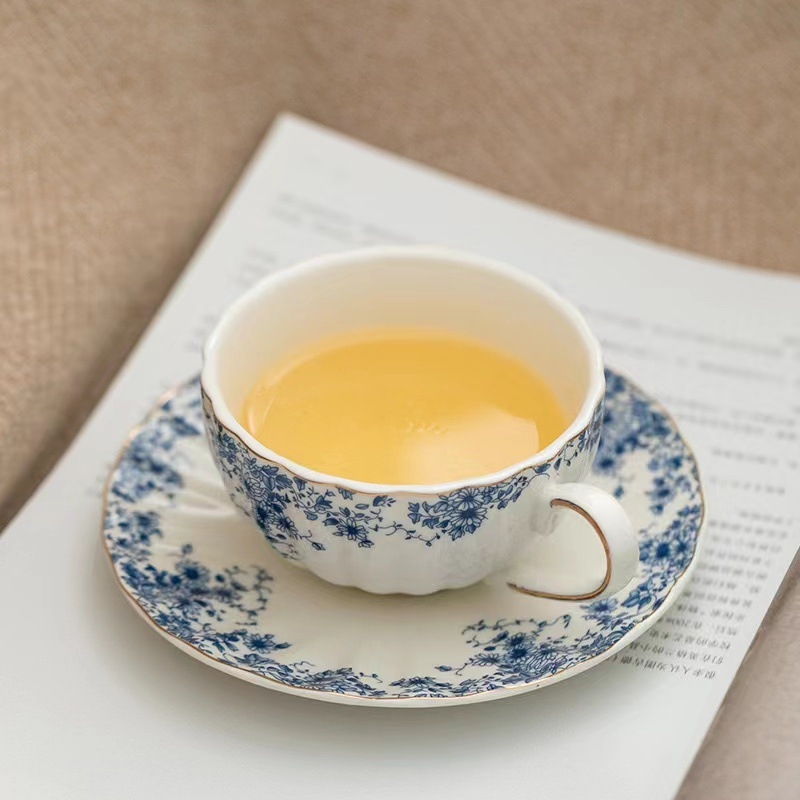 Set ceai în stil englezesc cu căni ceramice încălzite și farfurioare albastre cu flori pentru ceai și cafea