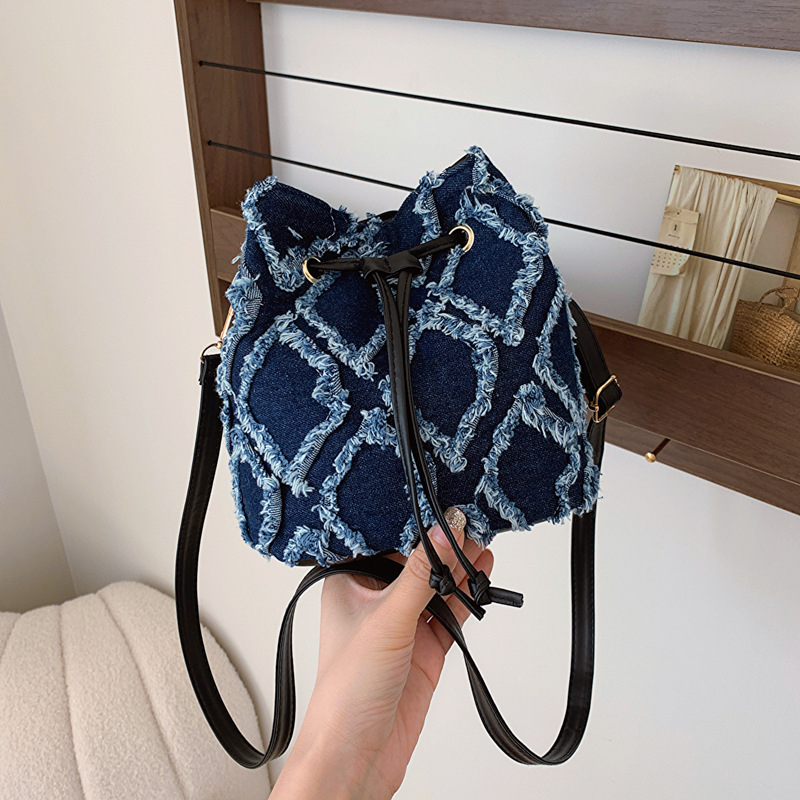 Mini bucket torbica s dijamantnim šivanjem, denim, špaga za zatvaranje i kićanka, preko ramena
