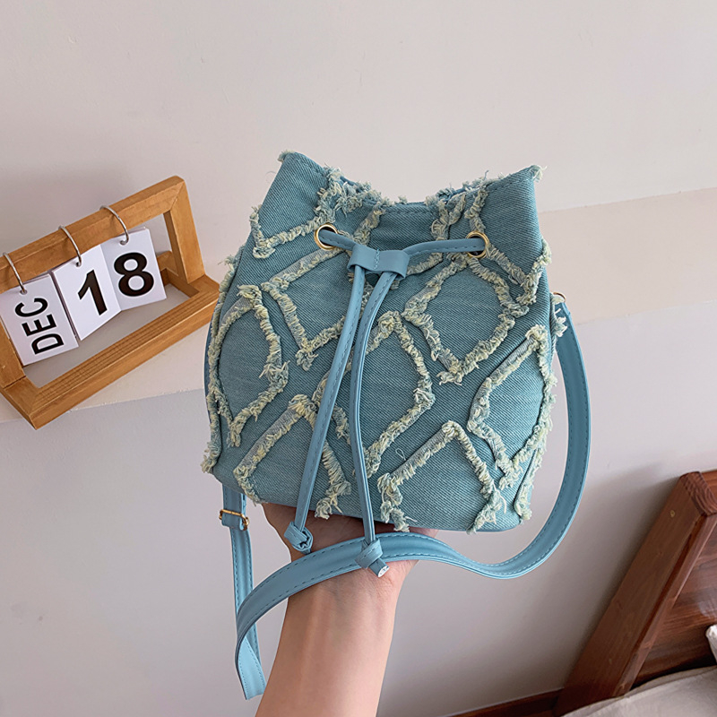 Mini bucket torbica s dijamantnim šivanjem, denim, špaga za zatvaranje i kićanka, preko ramena