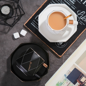 Set ceramic creativ pentru cafea: ceașcă, farfurioară, tavă cu margine aurie și lingură.