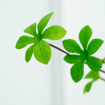 Plantă artificială verde, cu ramură agățată în formă de clopot și frunze cu mai mulți loburi, pentru decorul sufrageriei și al mesei