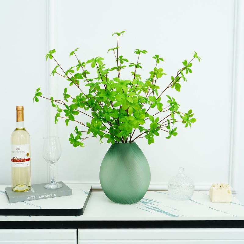 Plantă artificială verde, cu ramură agățată în formă de clopot și frunze cu mai mulți loburi, pentru decorul sufrageriei și al mesei