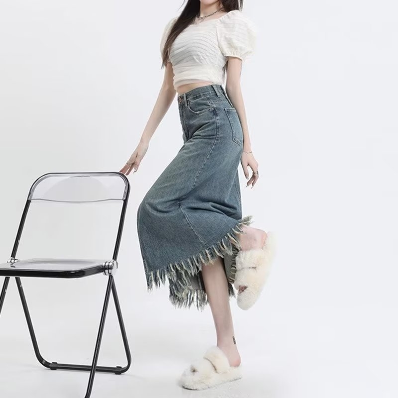 Retro denim suknja visokog struka s prednjim izrezom i resicama, srednje duljine, A-linije kroja.