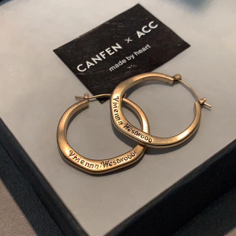 Ženske metalne naušnice s literom u kružnici — minimalističke brončane nijanse, elegantne i svestrane