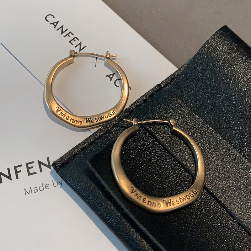 Ženske metalne naušnice s literom u kružnici — minimalističke brončane nijanse, elegantne i svestrane