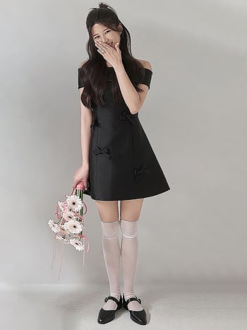 Rochie de seară neagră din satin, scurtă, în stil Hepburn, fără bretele, decolteu pe umeri, funda; eleganță minimalistă de înaltă calitate