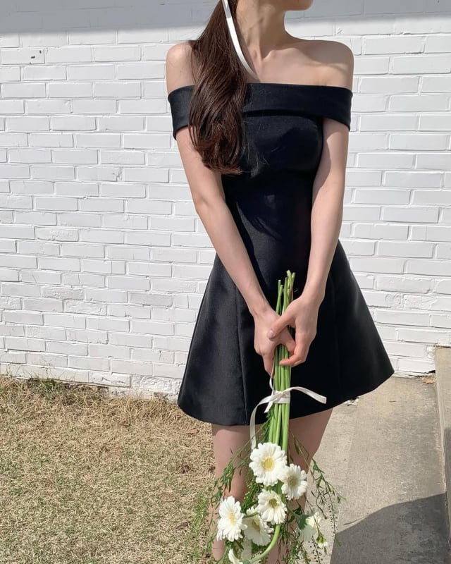 Rochie de seară neagră din satin, scurtă, în stil Hepburn, fără bretele, decolteu pe umeri, funda; eleganță minimalistă de înaltă calitate