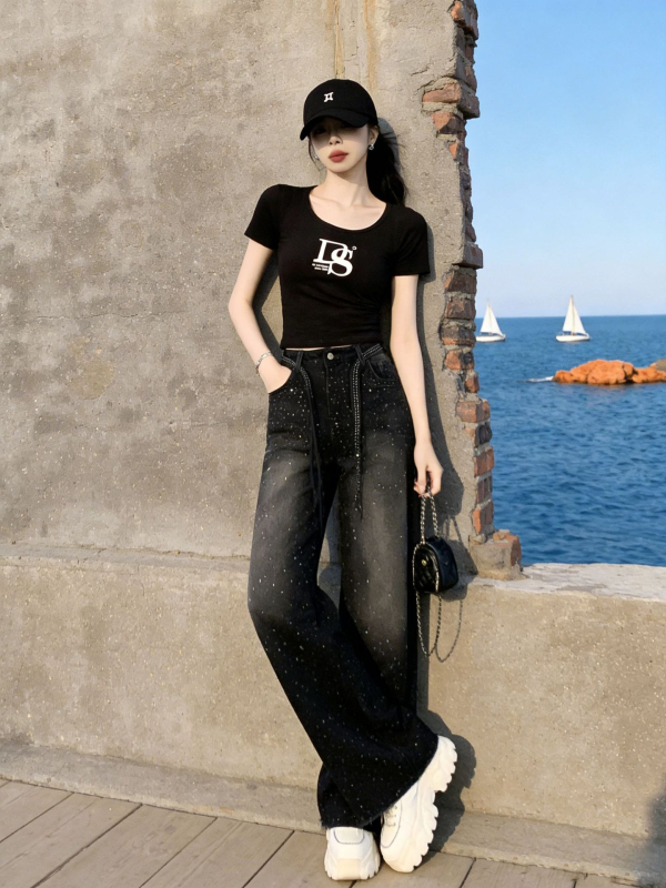 Σετ δύο τεμαχίων για γυναίκες με vintage streetwear: μαύρο T-shirt με εκτύπωση και στρας σε τζιν παντελόνι, casual καλοκαιρινό ντύσιμο.