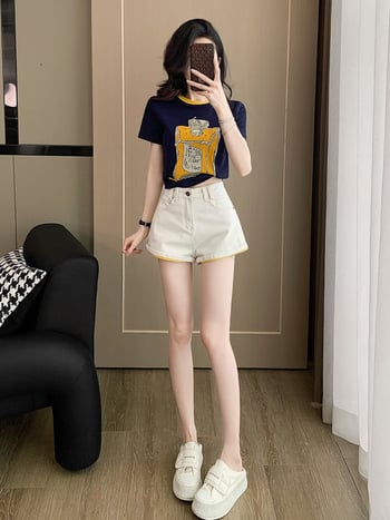 Γυναικείο σετ δύο τεμαχίων: T‑shirt με κοντό μανίκι, εκτύπωση σε αντίθεση και στρογγυλή λαιμόκοψη, ρολά στο τελείωμα, και λευκά τζιν σορτς.