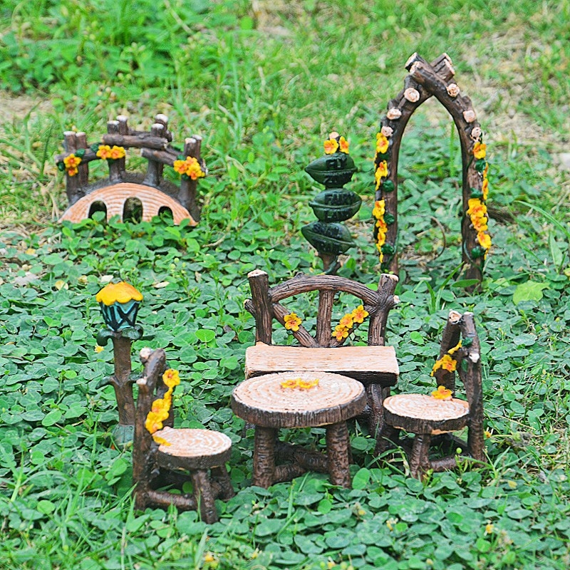 Miniatűr táj gyantából: fa szék és asztal, ív, híd, lámpa, útjelző tábla mohával.