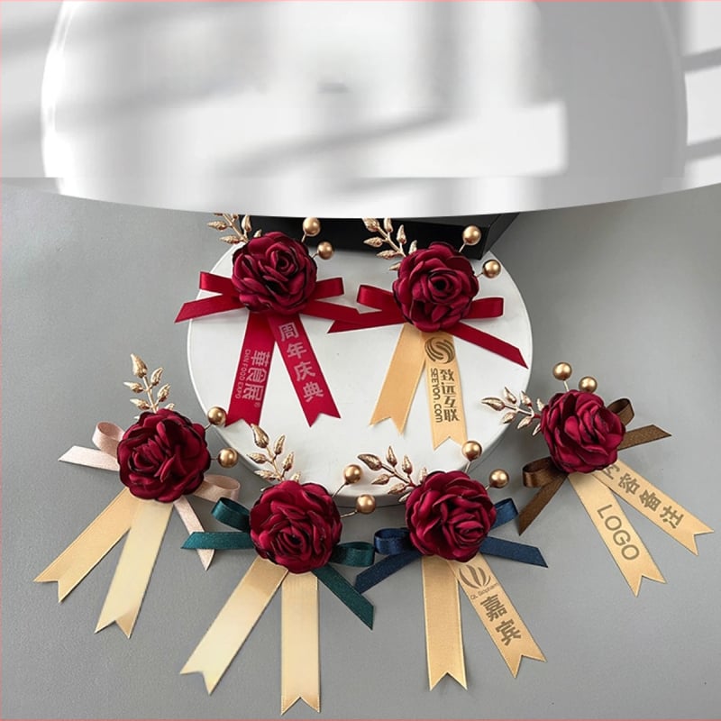 Magnetinė kokardė su šilko gėlyte ir įmonės logotipu, lipnus tvirtinimas; tinkama atidarymo ceremonijoms; verslo dovanos, reklaminės dovanos, susitikimų dovanos.