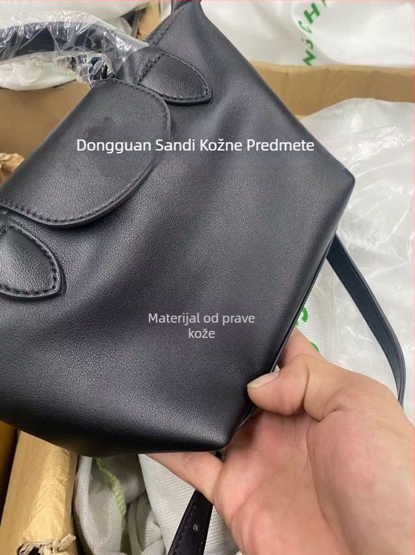 Torba od prave kože u obliku dumplinga s poklopcem, platnena podstava, unutarnji džepovi sa zipom, džep za telefon i osobnu iskaznicu, jedna naramenica