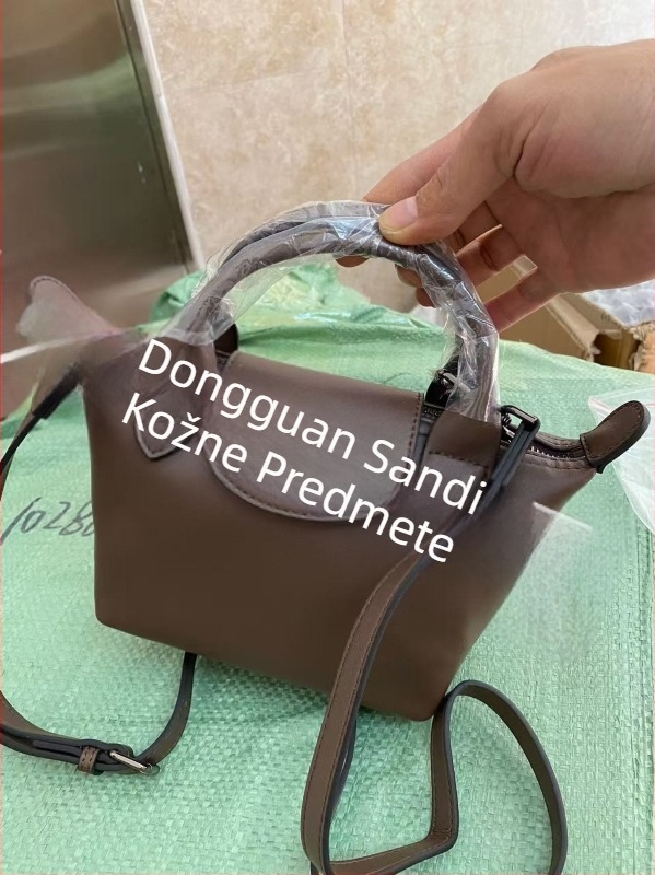Torba od prave kože u obliku dumplinga s poklopcem, platnena podstava, unutarnji džepovi sa zipom, džep za telefon i osobnu iskaznicu, jedna naramenica