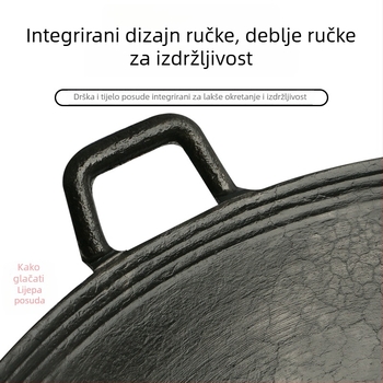 Dvoručna posuda od lijevanog željeza za kućnu upotrebu, tradicionalno seosko drveno ognjište.