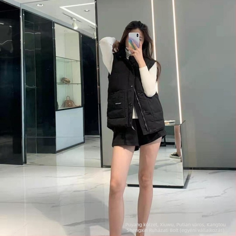 Mellény tollal töltött, álló gallérral, cipzárral; töltet: lúd toll; tartalom: 81–85%; fő anyag: poliészter; hossz: 50–65 cm