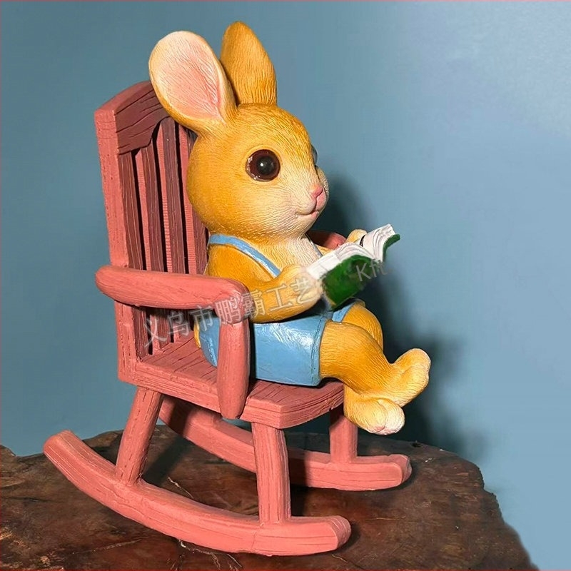 Olvasó nyúl hintázó székkel – kültéri dekoráció kertbe és erkélyre, cartoon stílusú, szintetikus gyantából készült