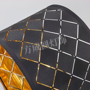 Textil lámpabura fekete külsővel és arany belsővel, üreges gravírozott mintával.