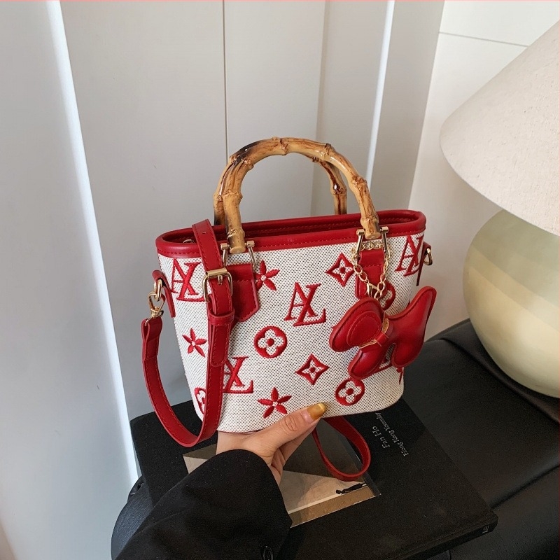 Vödrös táska betűkkel nyomtatva, fa fogantyúval, vállon vagy crossbody viselésre.