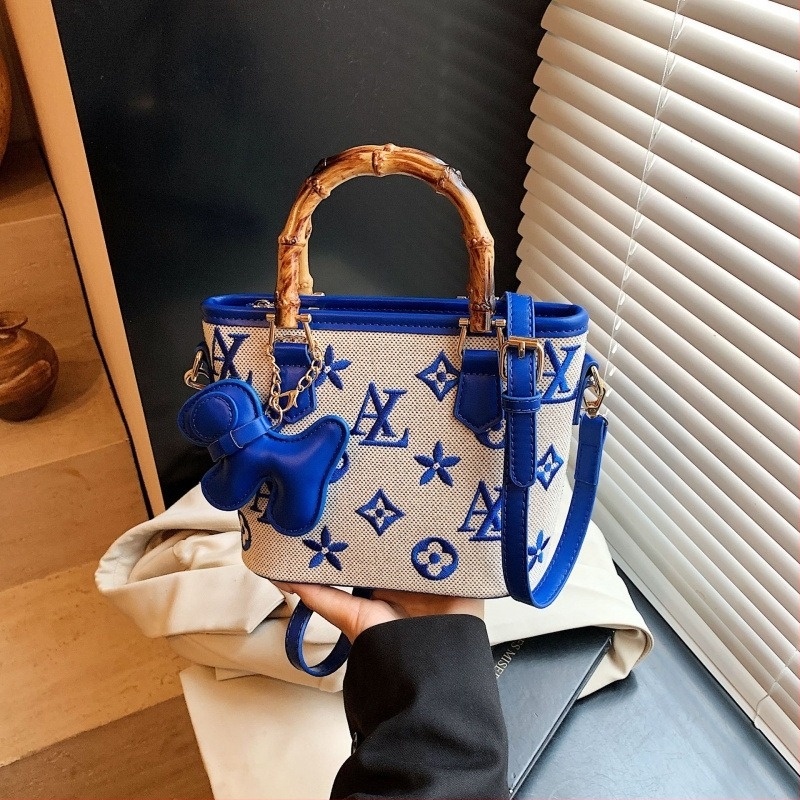 Vödrös táska betűkkel nyomtatva, fa fogantyúval, vállon vagy crossbody viselésre.