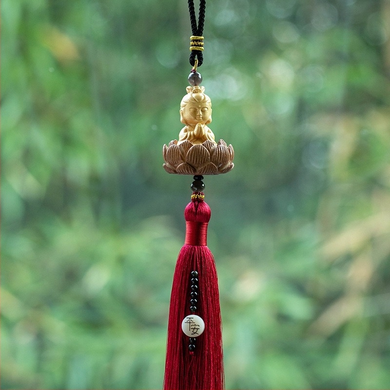 Pandantiv auto din lemn cu Buddha mic, bază de lotus și ciucuri lungi; decor interior modern.