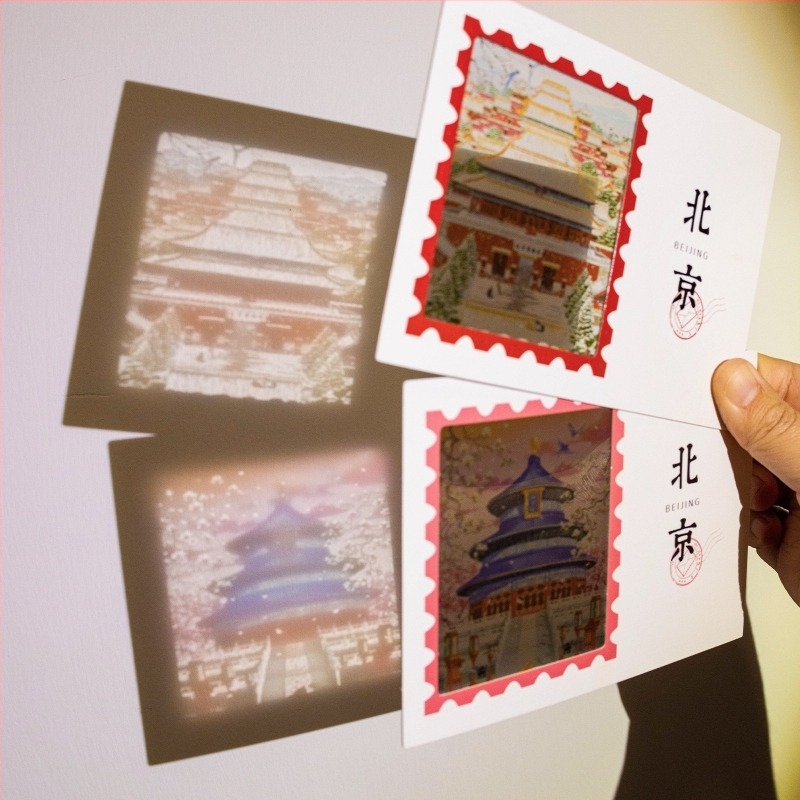 Carte poștală translucidă cu Orașul Interzis din Beijing în zăpadă, ziduri roșii și arhitectură veche, patru anotimpuri, în culori vii.